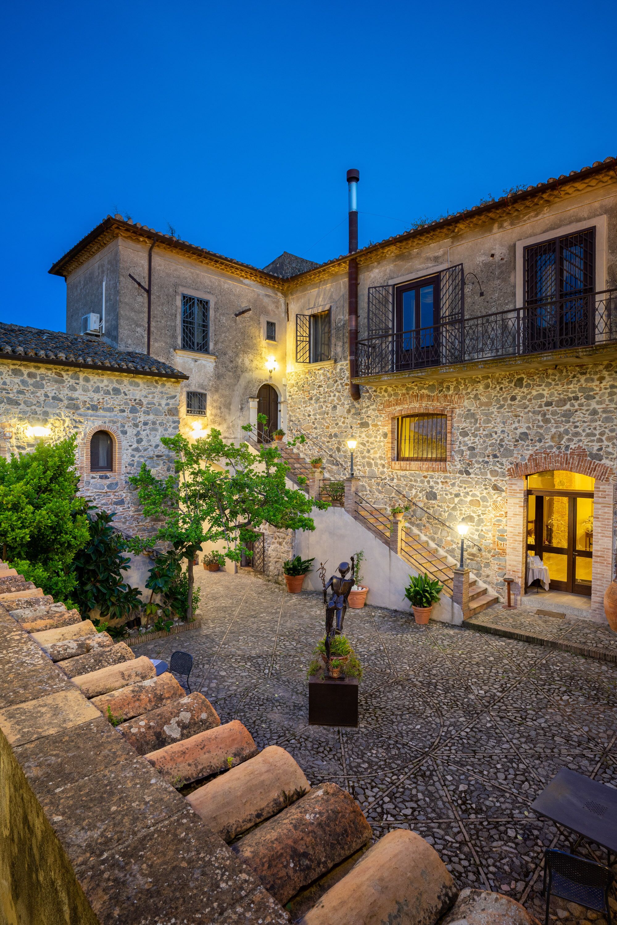 Un patio con edificios de piedra, una escalera y mobiliario para exteriores.