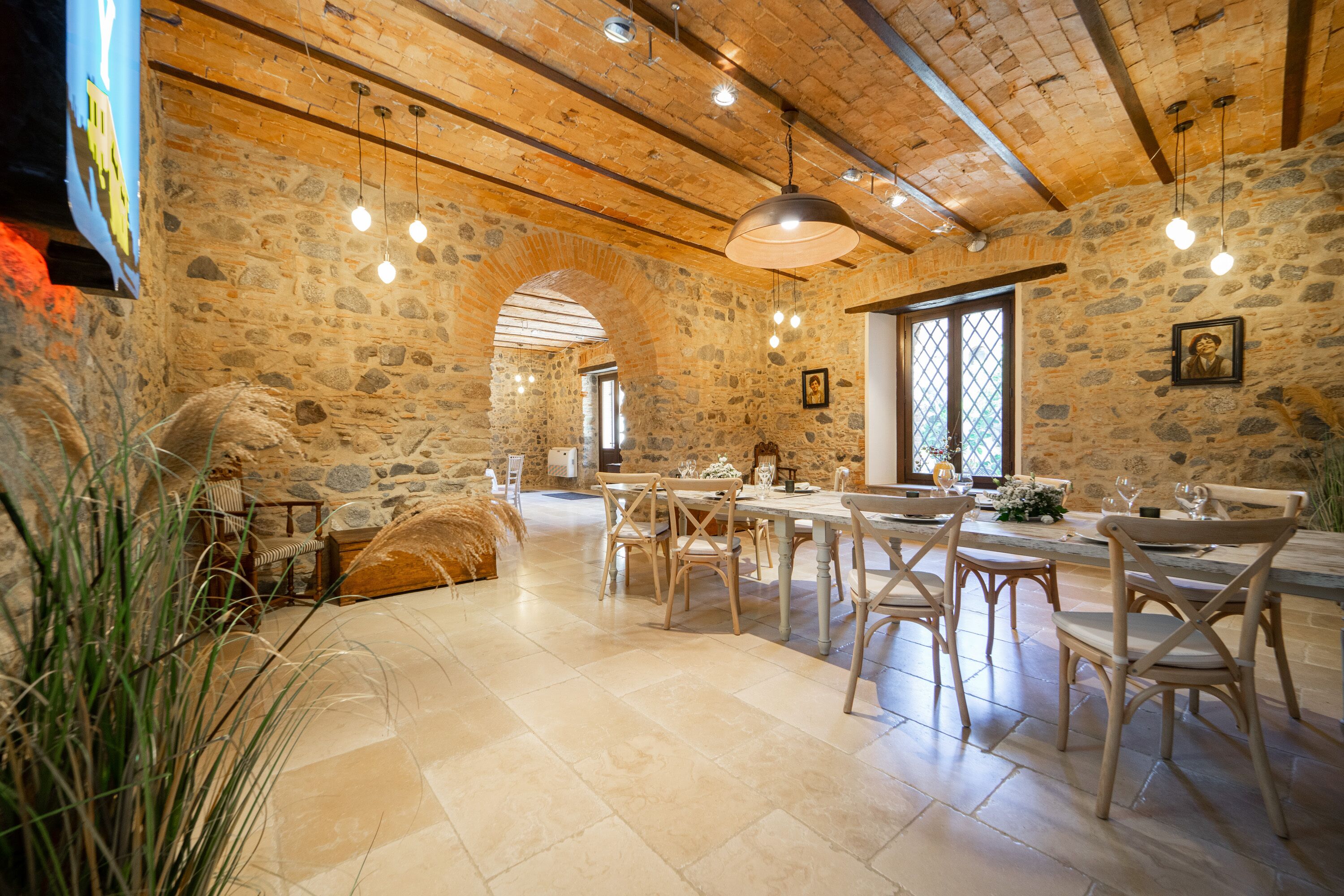 Un comedor rústico con paredes de piedra, vigas de madera y una mesa grande con sillas.