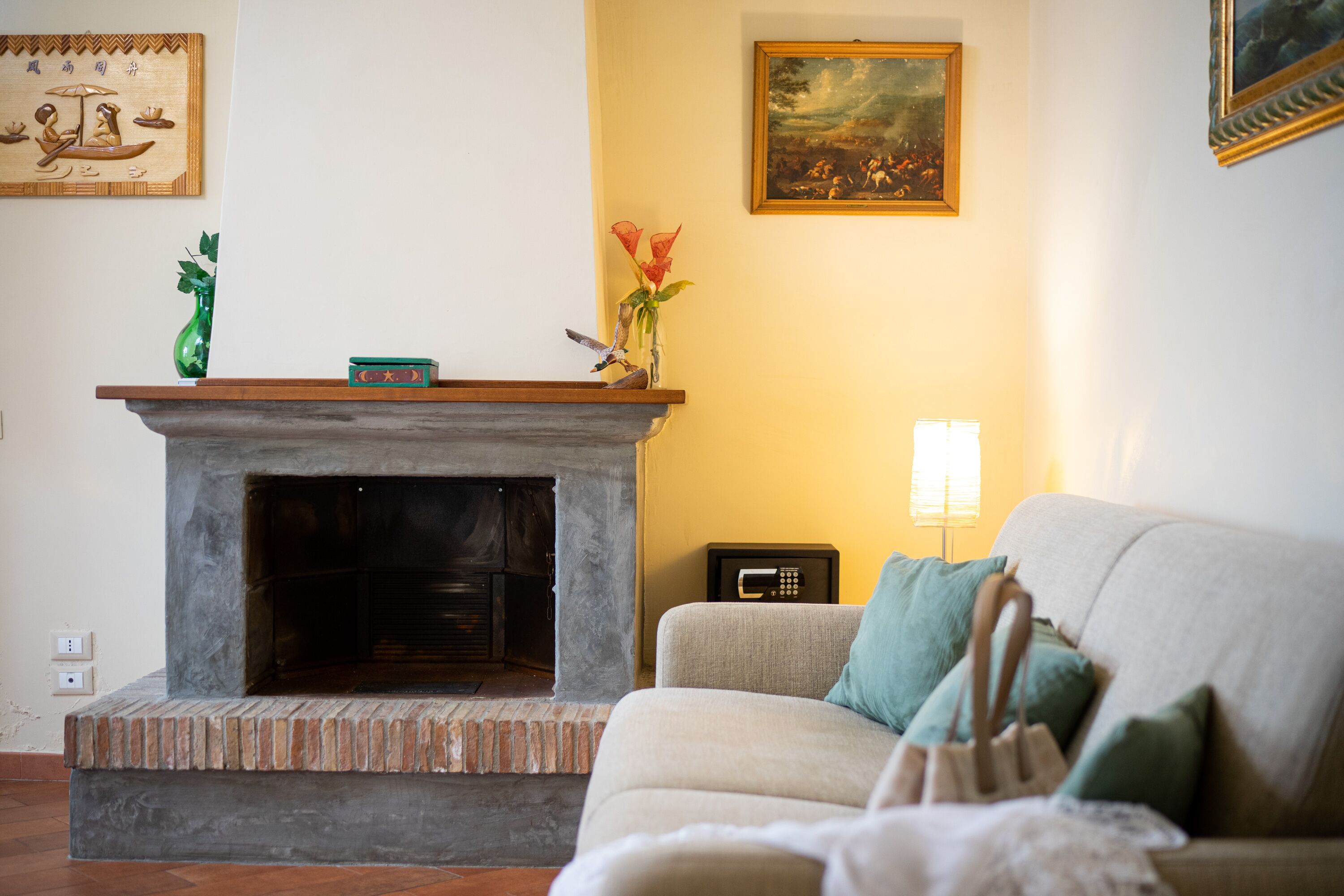 A living room with a fireplace, a sofa, and a painting on the wall.