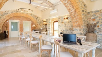 A spacious dining area with a long table, several chairs, and a laptop on the table.