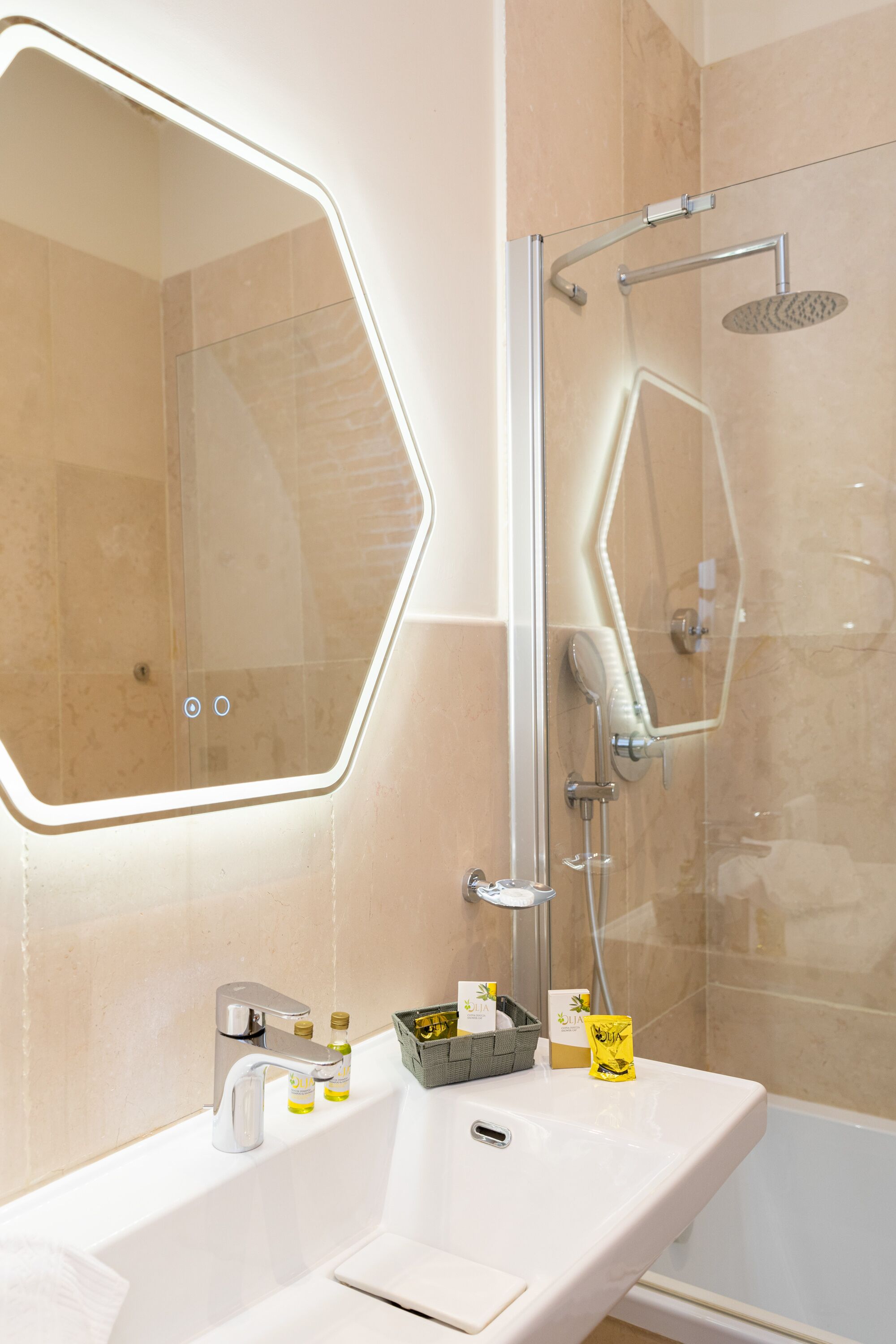 Ein modernes Badezimmer mit einem sechseckigen Spiegel, einem weißen Waschbecken und einer Duschkabine.