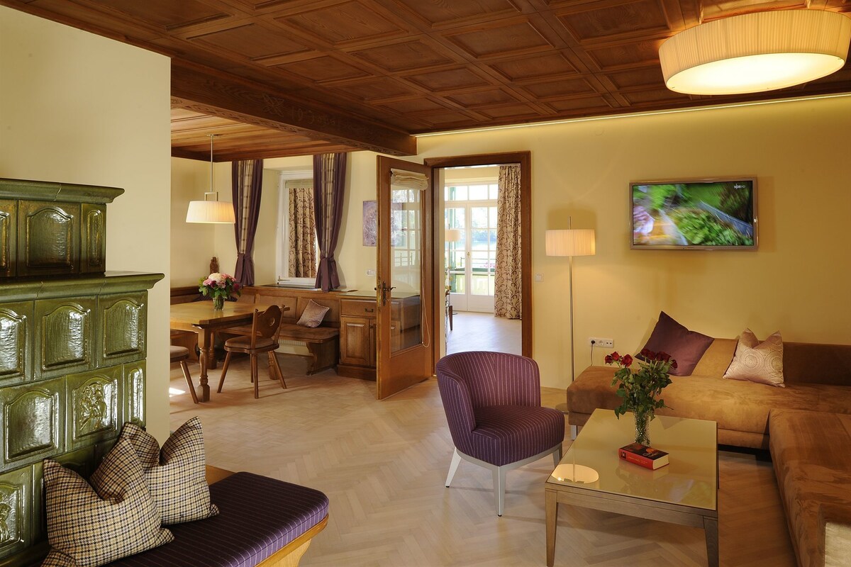 Un salón espacioso con techo de madera, un sofá, una mesa de comedor y un televisor.