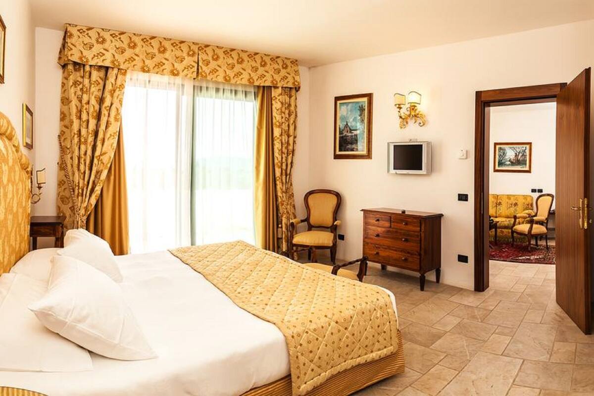 A hotel room with a bed, a desk, a chair, and a television.