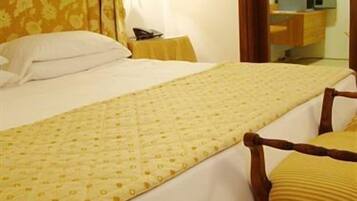 Una habitación de hotel con una cama grande, una mesita de noche, una silla y un armario.