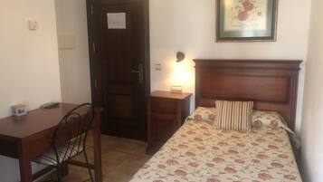 A bedroom with a bed, a nightstand, a desk, and a chair.