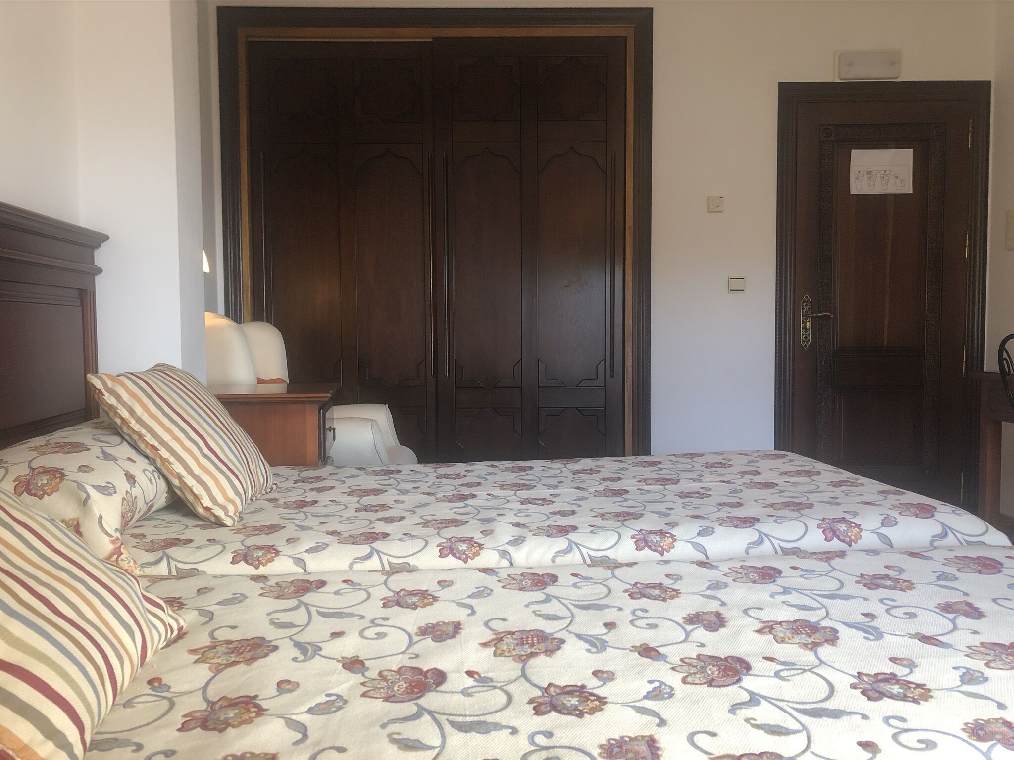 A bedroom with a bed, a nightstand, a chair, and a wardrobe.