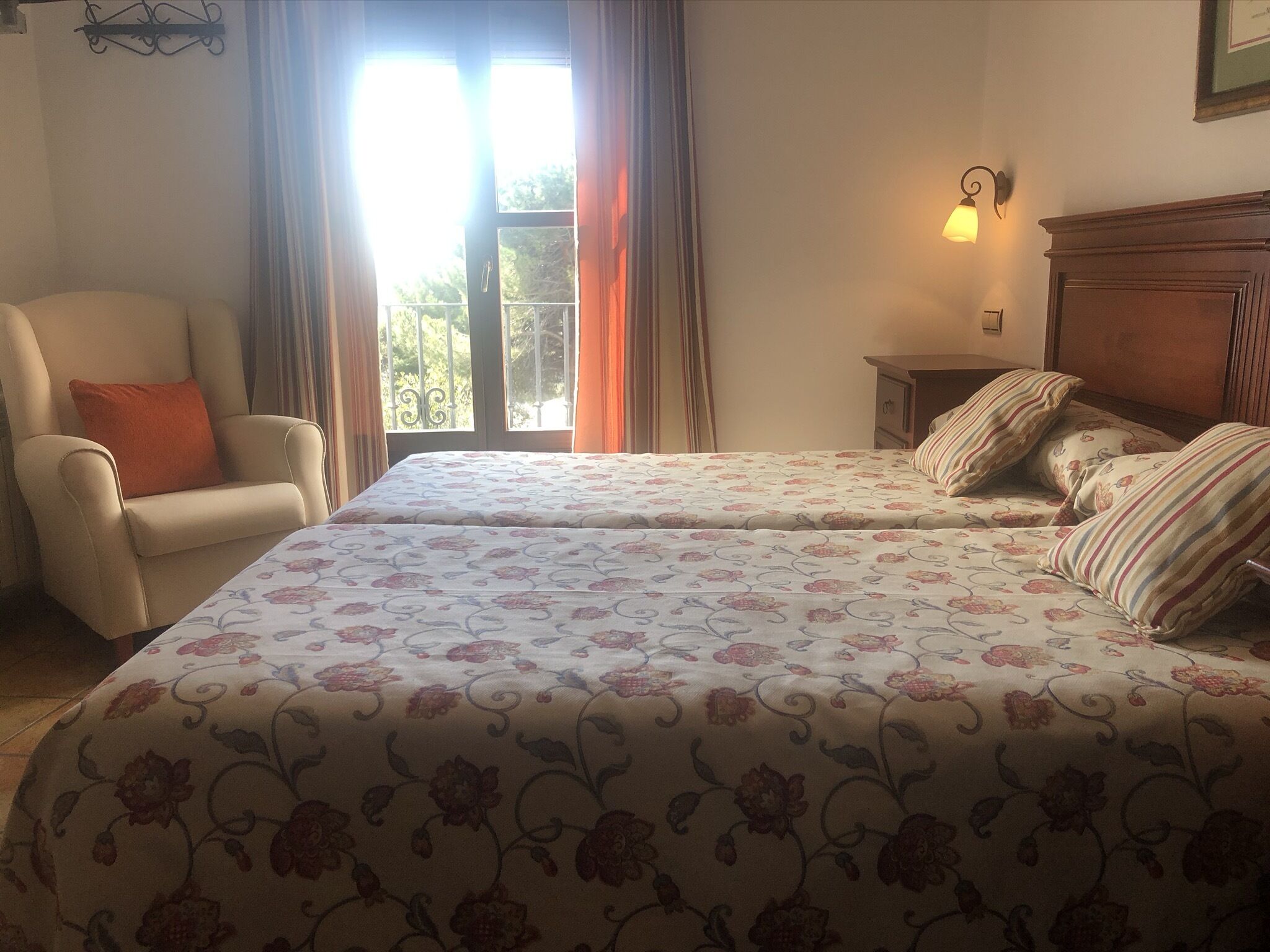 Un dormitorio con dos camas, una silla, una mesita de noche y una ventana con cortinas.