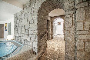 A stone-walled indoor pool area with a clear pathway leading to a door. - Hotel Serles (Mieders)