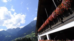 A building with balconies adorned with flowers, set against a mountainous backdrop. - Hotel Serles (Mieders)