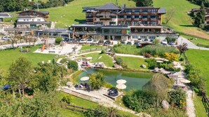 Un hotel con varias plantas, piscina al aire libre y un jardín ajardinado.