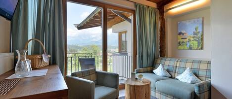 A cozy living area with a wooden ceiling, a sofa, a chair, a small round table, and a TV on a stand.