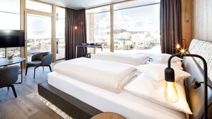 Una habitación de hotel moderna con una cama grande, un escritorio, una silla y un televisor.