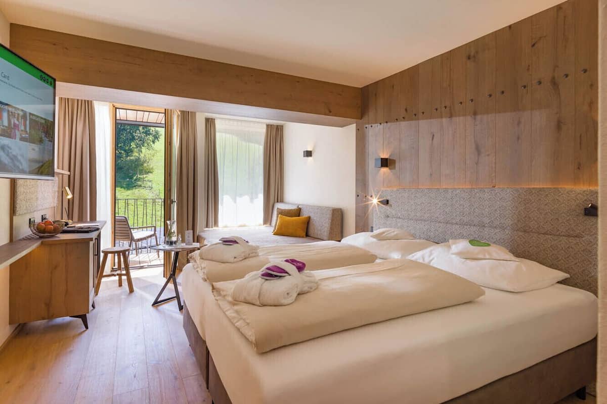 A hotel room with a large bed, a desk, a chair, and a TV.