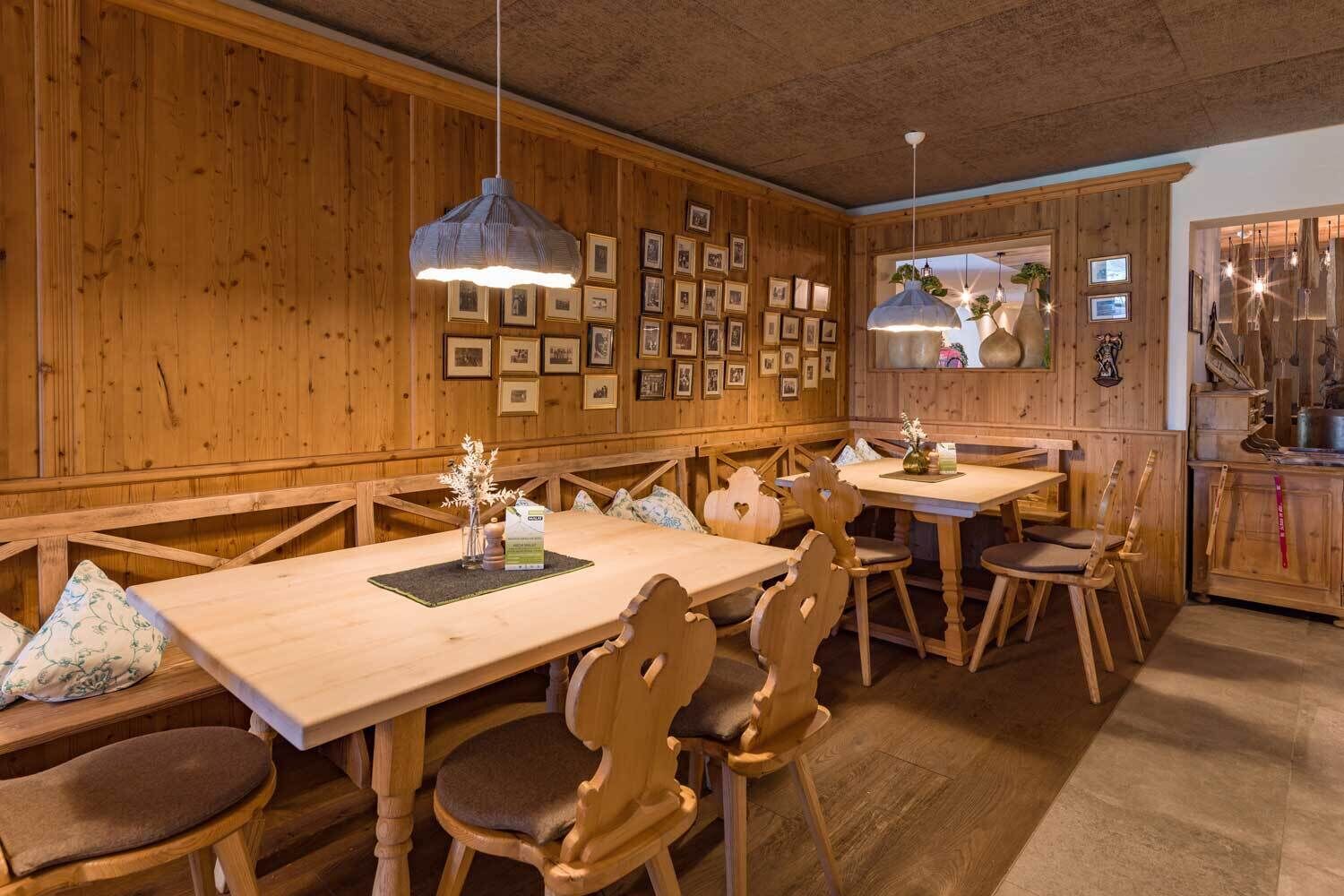 Un interior de madera con una larga mesa de comedor, bancos y lámparas colgantes.