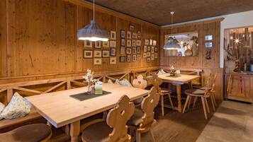 Un interior de madera con una larga mesa de comedor, bancos y lámparas colgantes.