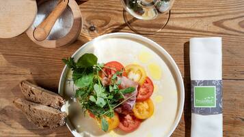 A plate of food with tomatoes, herbs, and a drizzle of olive oil, accompanied by slices of bread and a napkin with a green label.