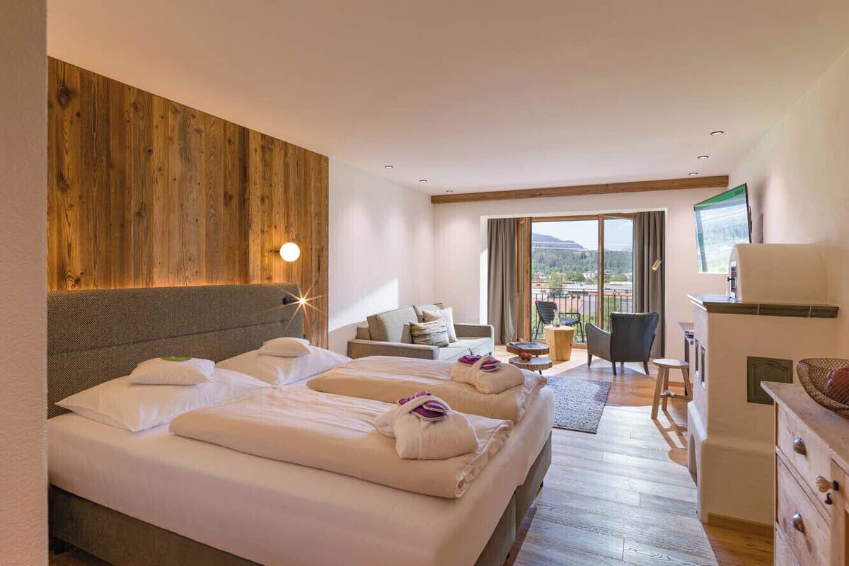 A hotel room with a large bed, a sofa, a TV, and a view of the outdoors.