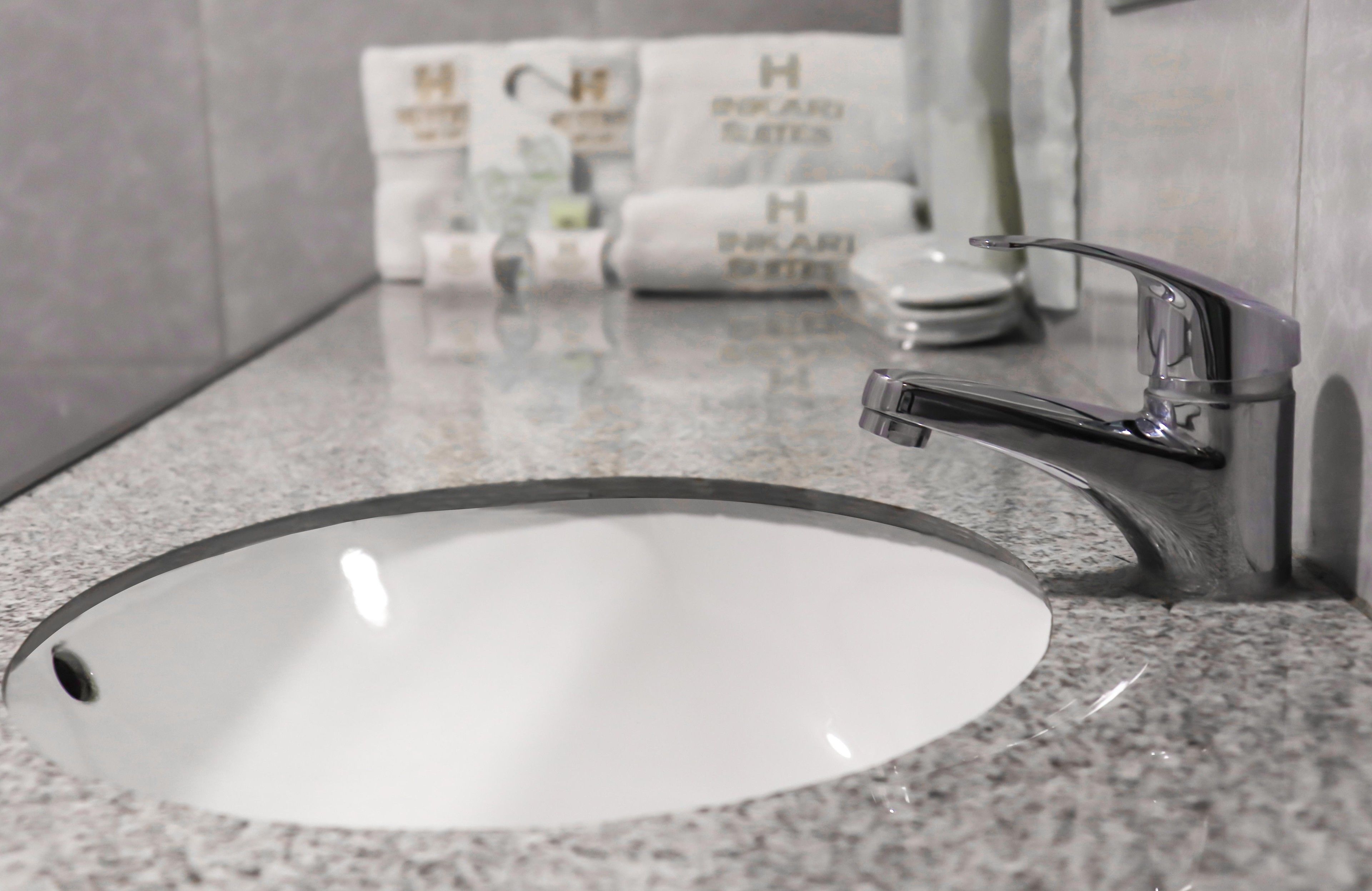 A bathroom with a granite countertop, a round sink, and a modern faucet.