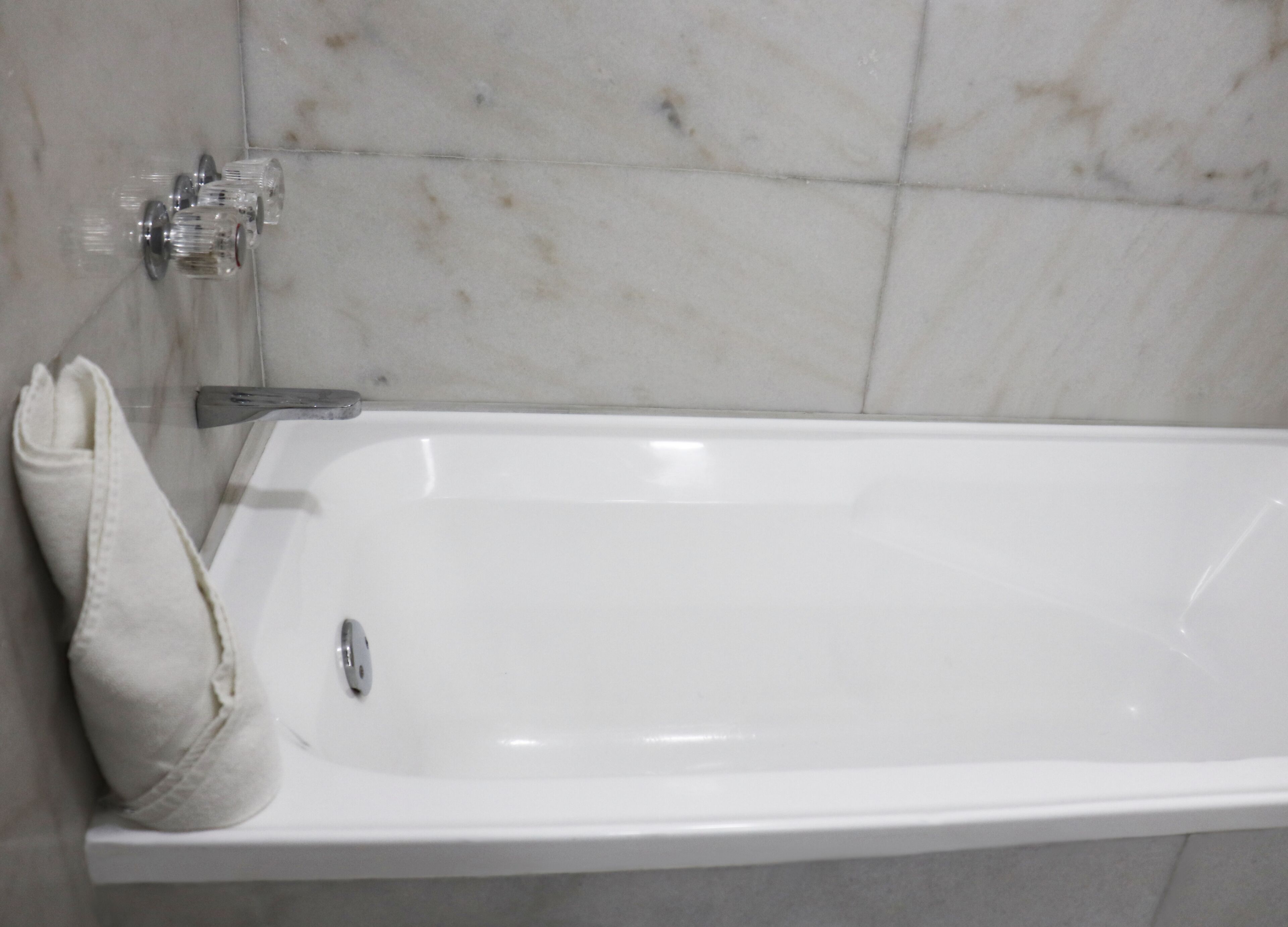 Una bañera blanca con grifo y una toalla colgada al lado.