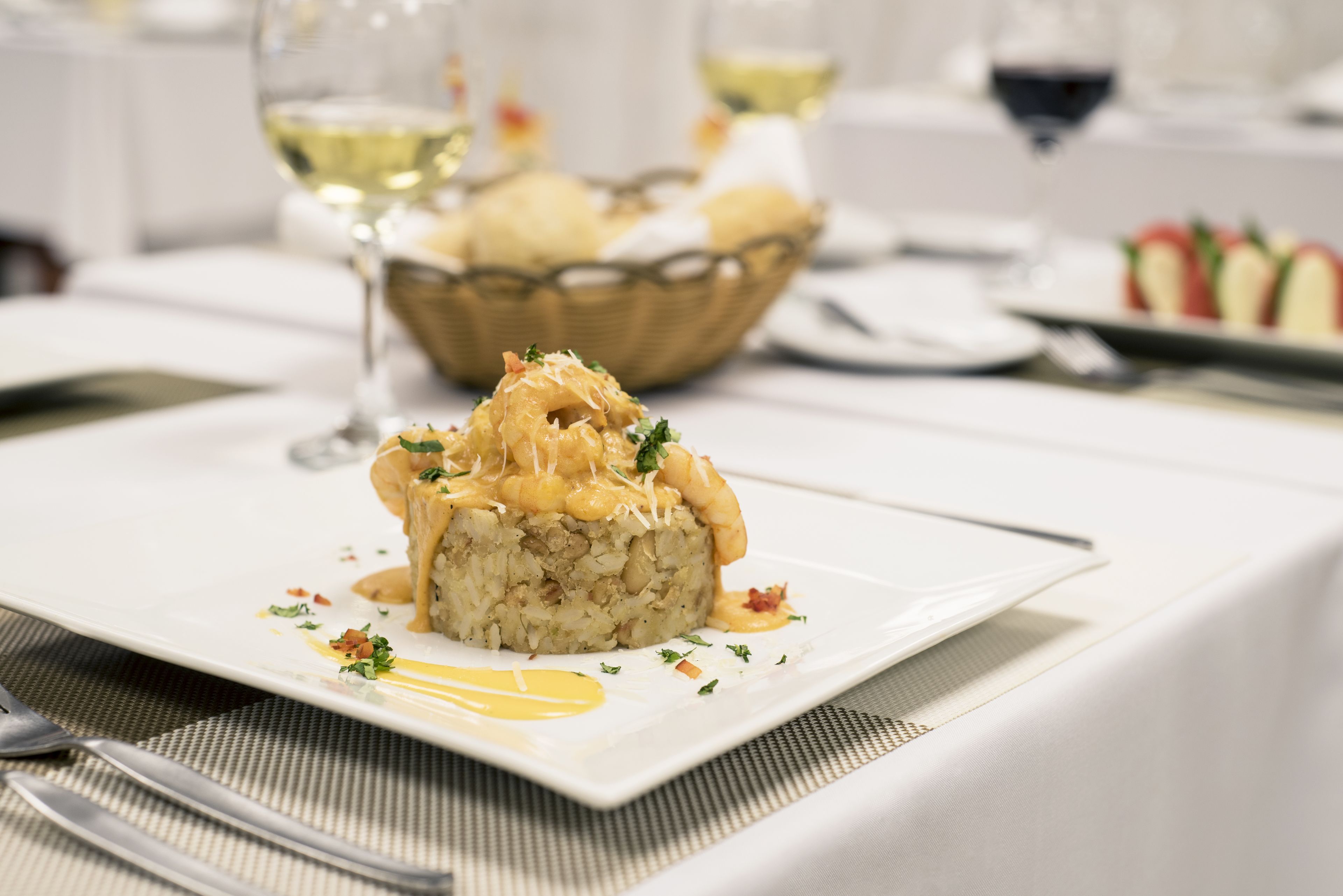 A plated dish with a creamy sauce, garnished with herbs, on a white square plate.