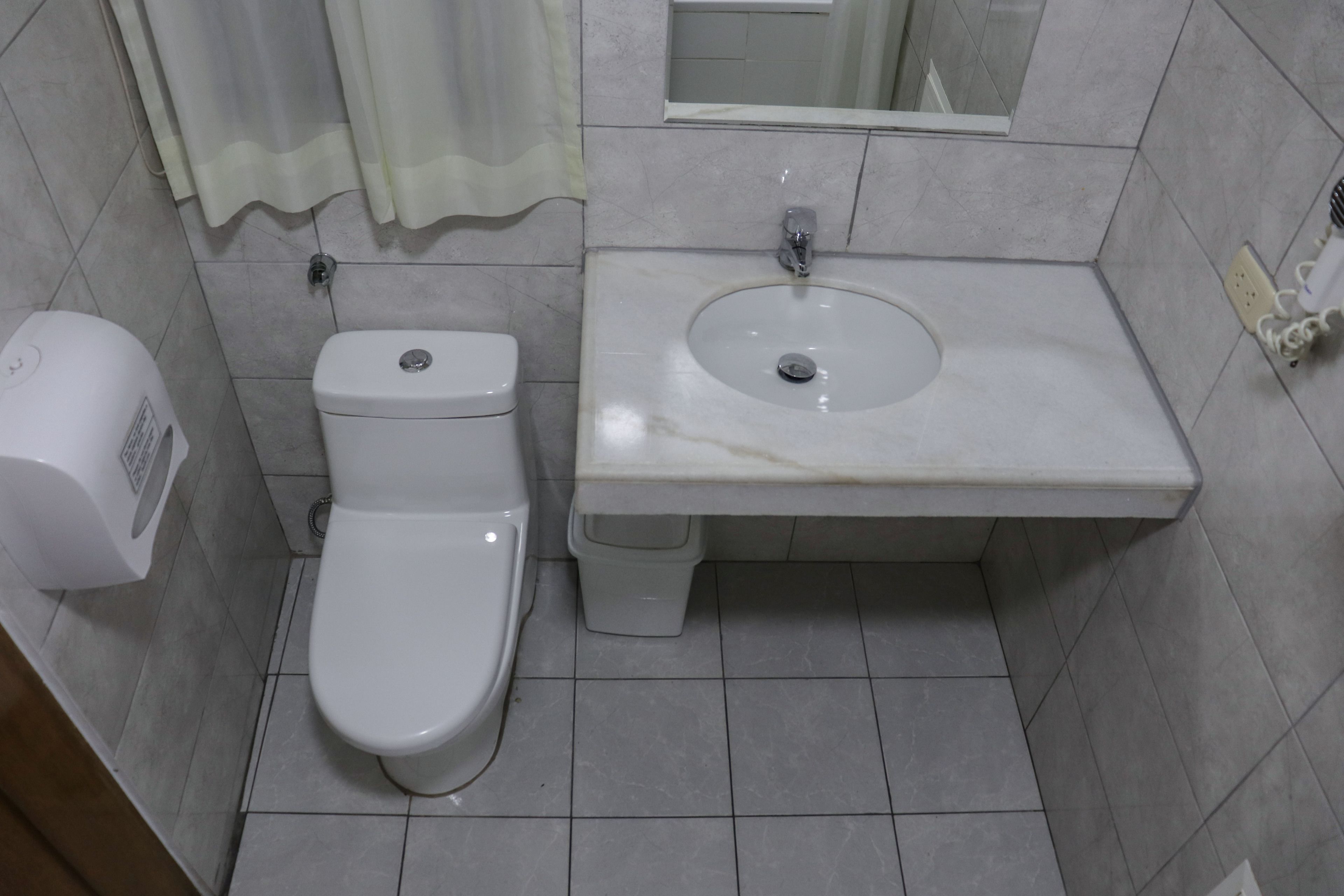 A bathroom with a toilet, sink, and a hand dryer.