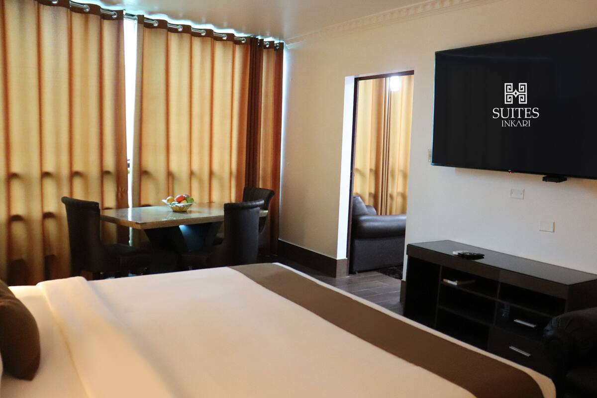 Una habitación de hotel con una cama grande, un escritorio con silla, televisión y un sofá.