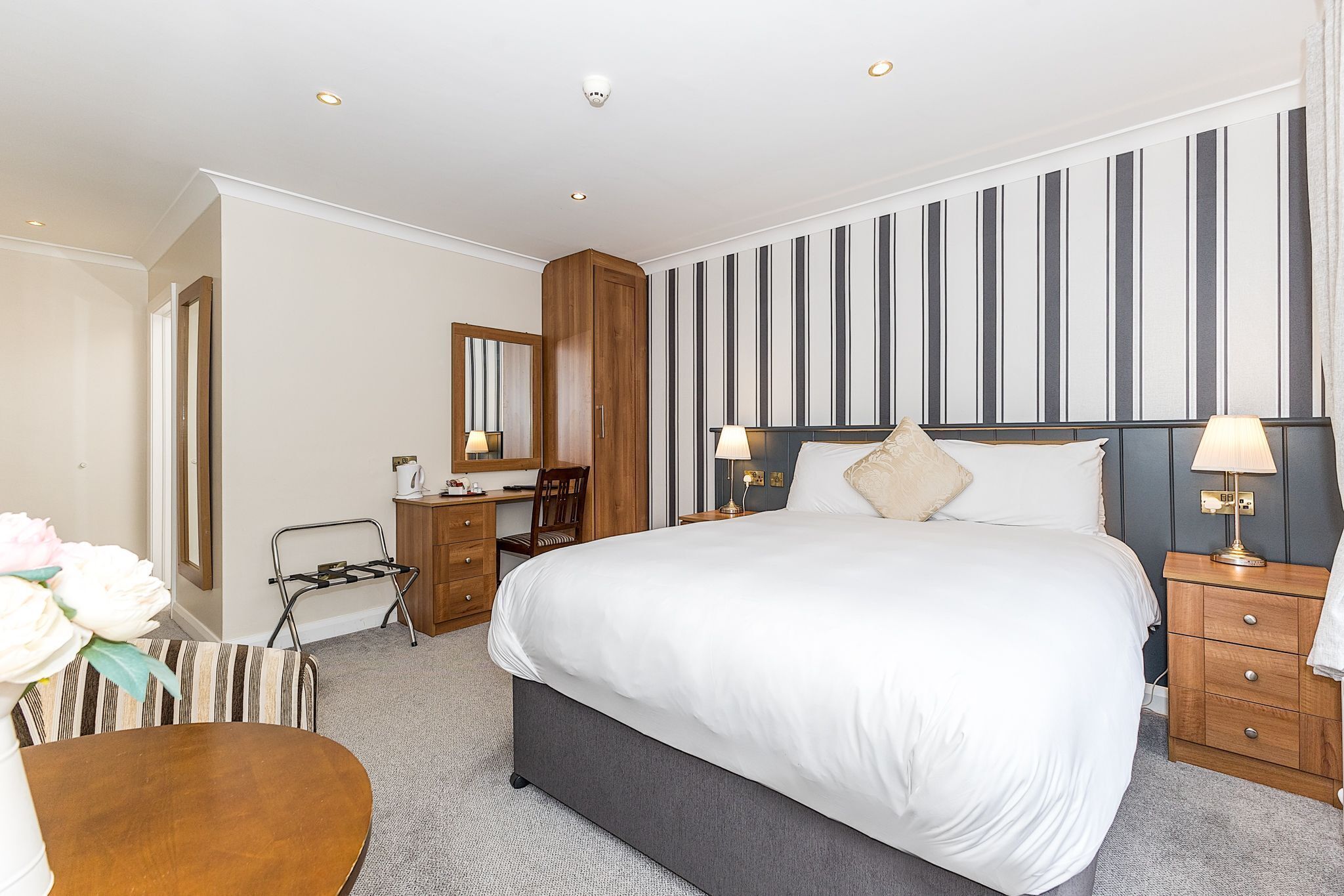 A hotel room with a large bed, bedside tables, a desk, and a chair.