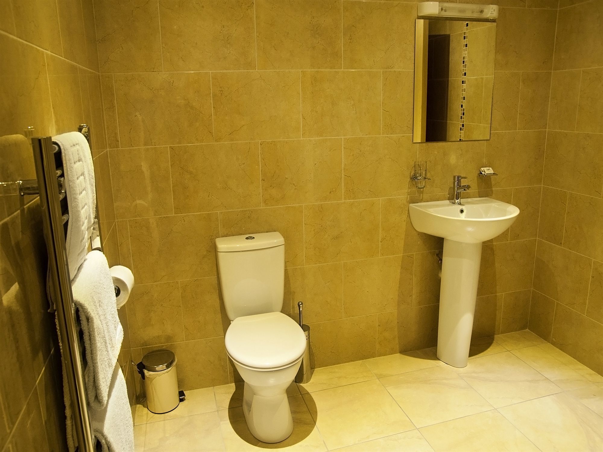 A bathroom with a toilet, sink, and a mirror.