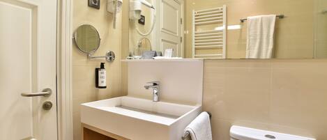 A modern bathroom with a sink, mirror, towel rack, and toilet.
