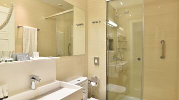 A modern bathroom with a glass-enclosed shower, a white sink, and a large mirror.
