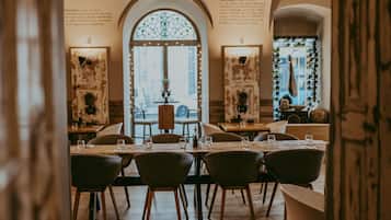 Un restaurante con un ventanal central en arco, mesas y sillas de madera.