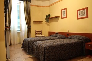 A hotel room with two beds, a wooden headboard, a small plant, and two framed pictures on the wall. - Hotel Cavallo Bianco (Novara)