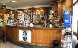 Zona de bar con mostrador de madera, varias botellas y un letrero con un logotipo de caballo.