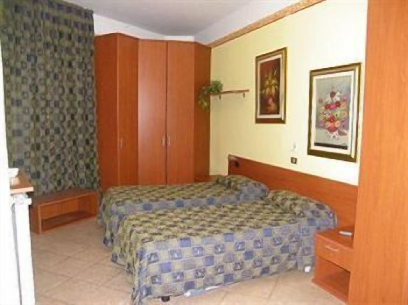 Ein Schlafzimmer mit zwei Betten, einem Kleiderschrank und einem kleinen Nachttisch.