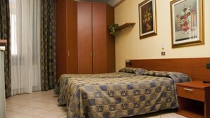 A bedroom with a bed, two bedside tables, a wardrobe, and a wall-mounted shelf with a plant. - Hotel Cavallo Bianco (Novara)