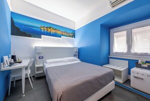Een slaapkamer met een bed, een bureau, een stoel, een nachtkastje, een dressoir en een raam met jaloezieën.