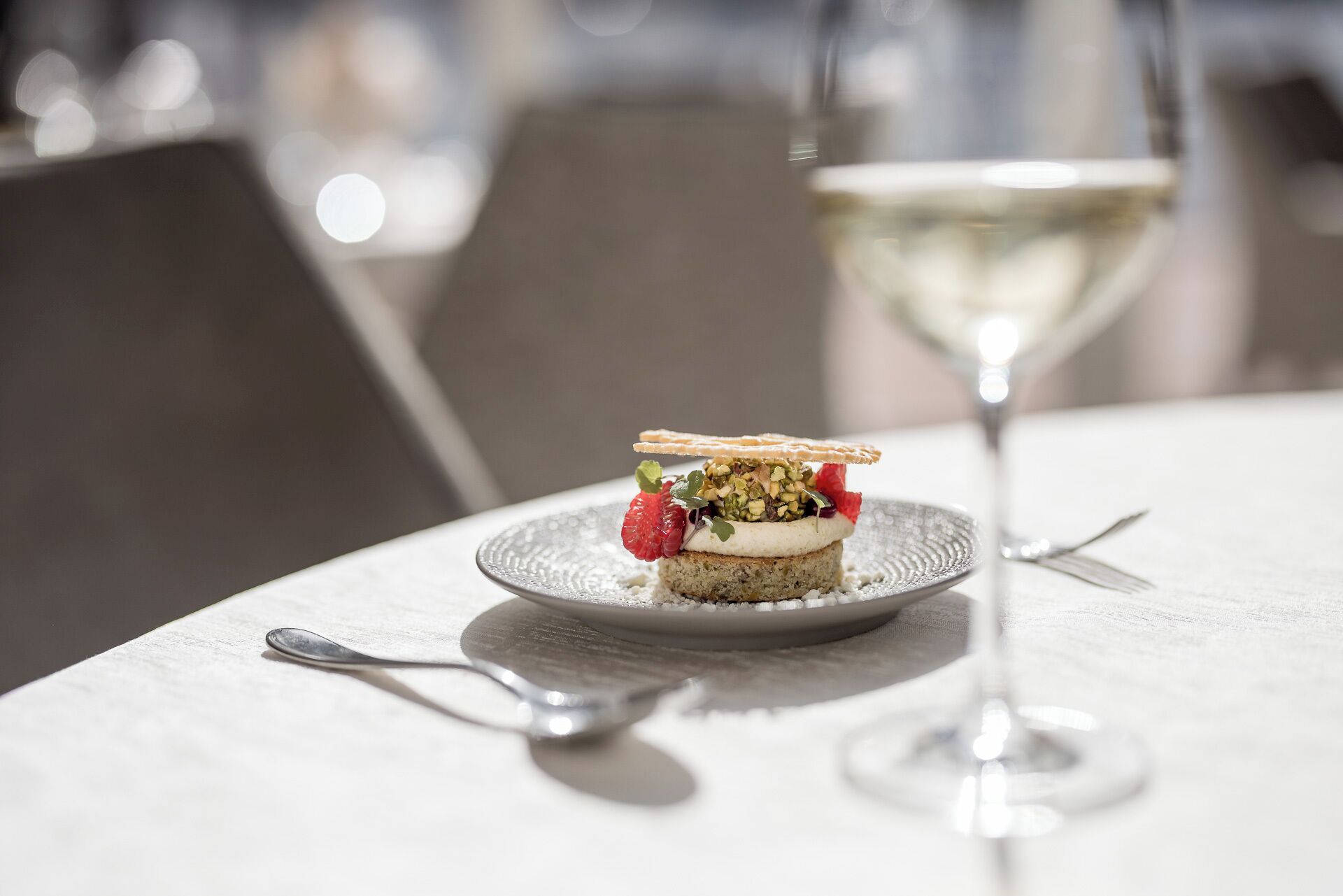 A dessert on a plate with a glass of white wine on a table.
