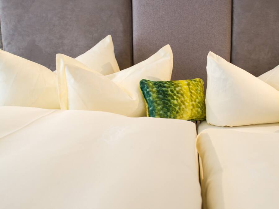 Una cama con varias almohadas, un cabecero con un diseño geométrico y un cabecero tapizado en gris.