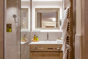 A modern bathroom with a glass-enclosed shower, a vanity with a sink, and a mirror with an ornate frame.