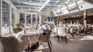 A restaurant with a glass ceiling, tables set for dining, and a view of snow-covered mountains. - Hotel Rita (Laengenfeld)