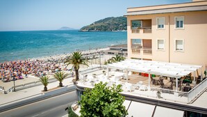 A beachside hotel with outdoor seating, a view of the sea, and a hillside in the background. - Hotel Villa Eleonora (Minturno)
