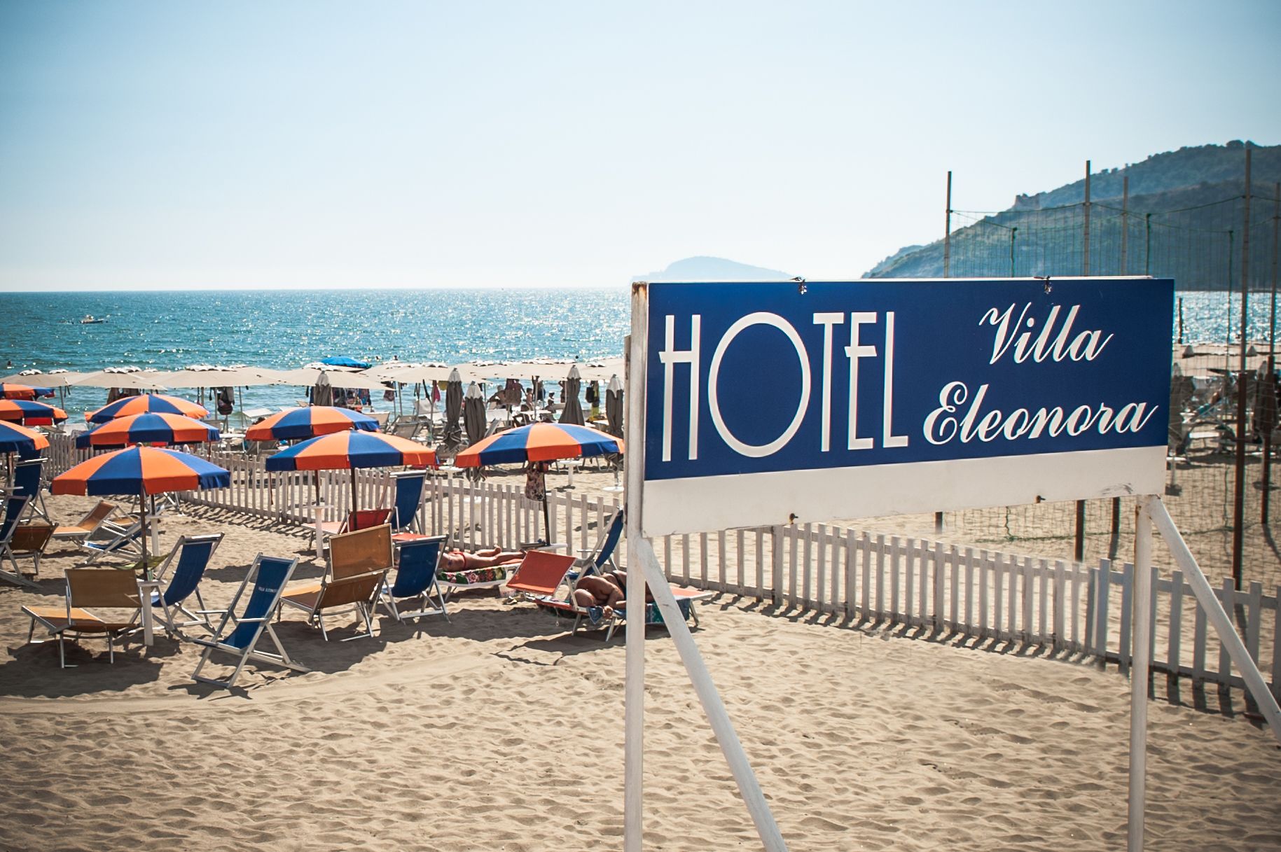 A beachside hotel sign with "HOTEL Villa Eleonora" written on it.