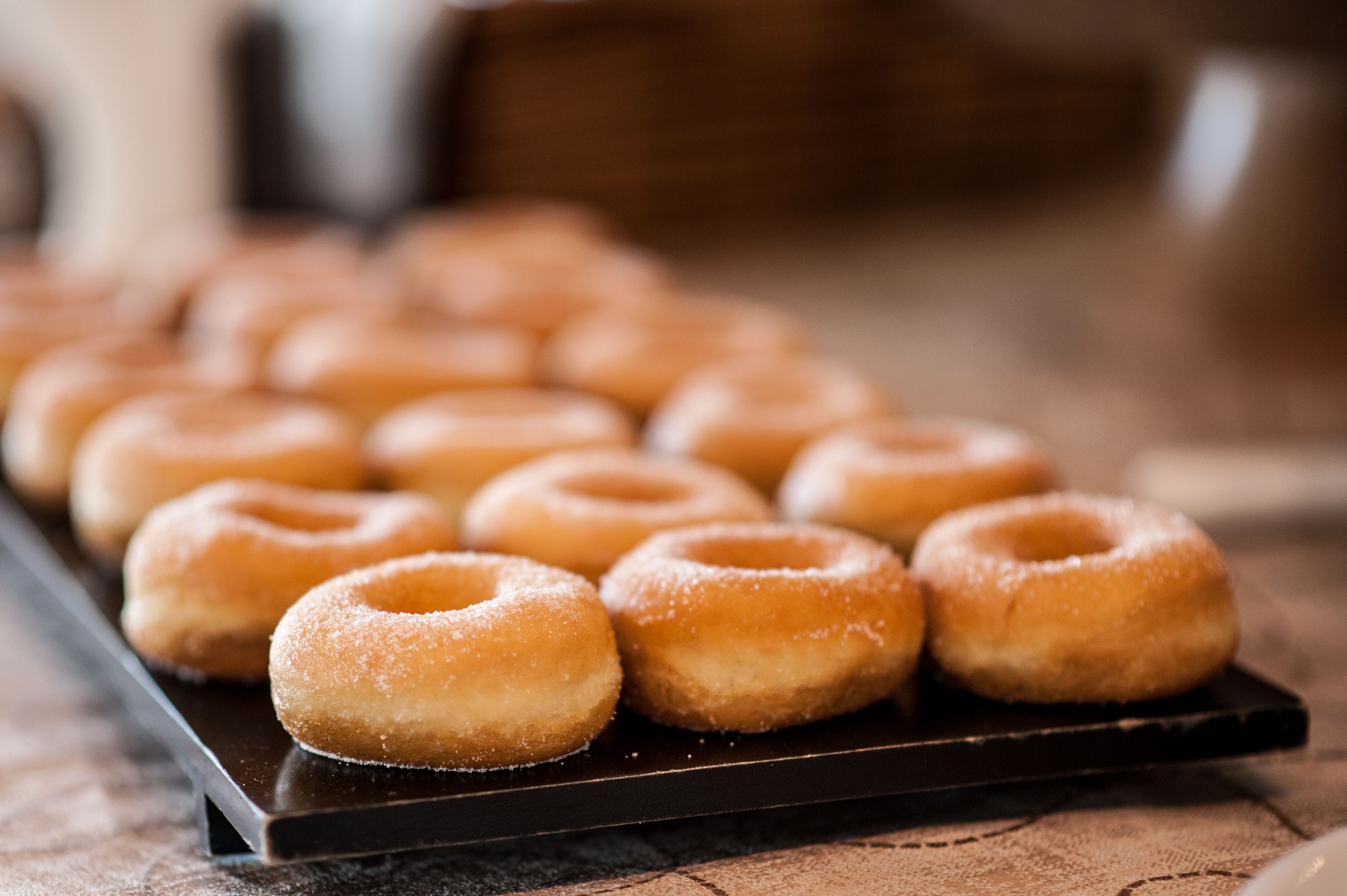 Une barquette de beignets glacés sur une surface en bois.
