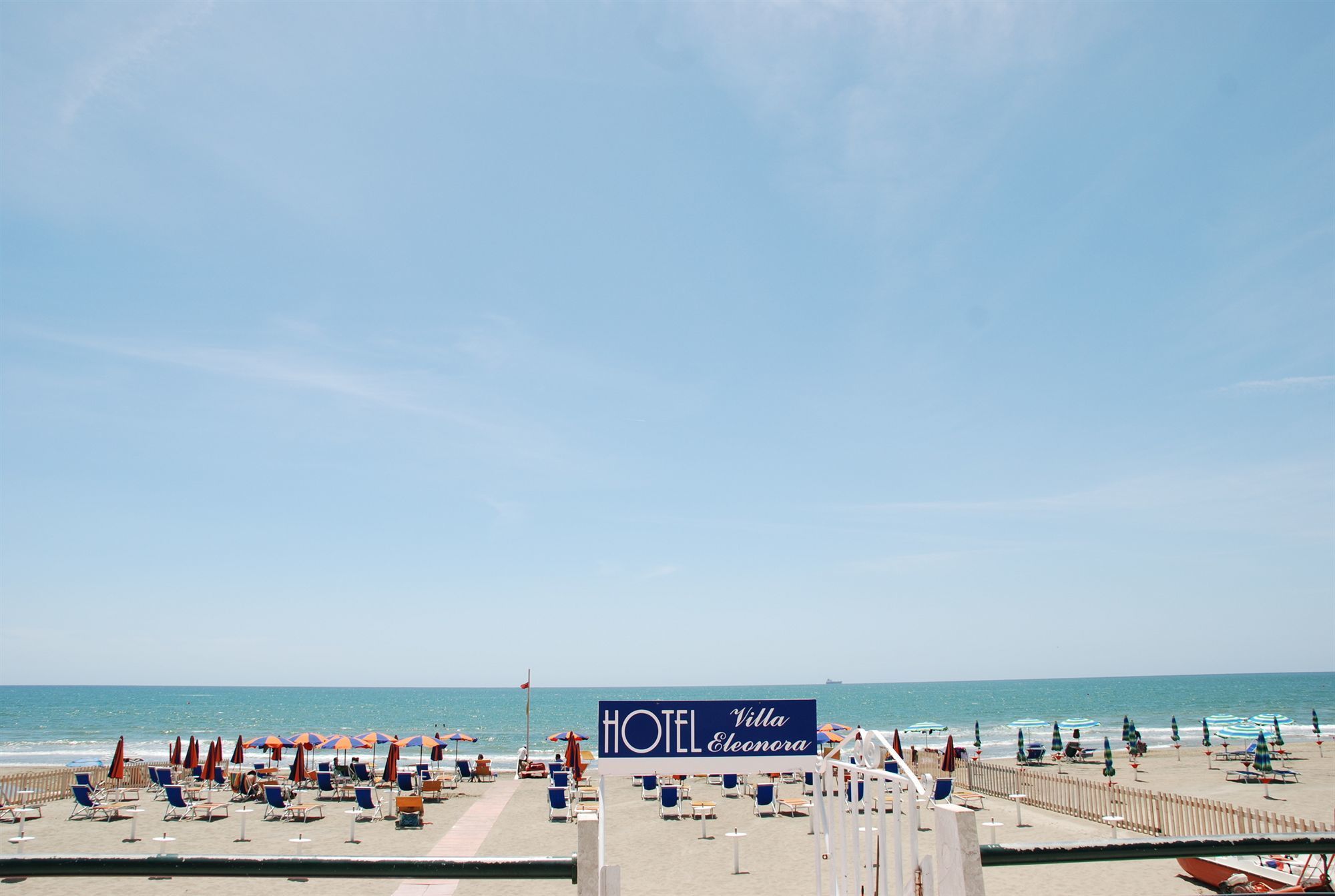 A beach view with a sign for HOTEL Villa Eleonora.