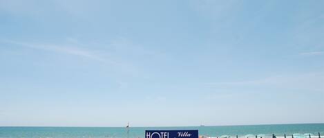 A beach view with a sign for HOTEL Villa Eleonora.