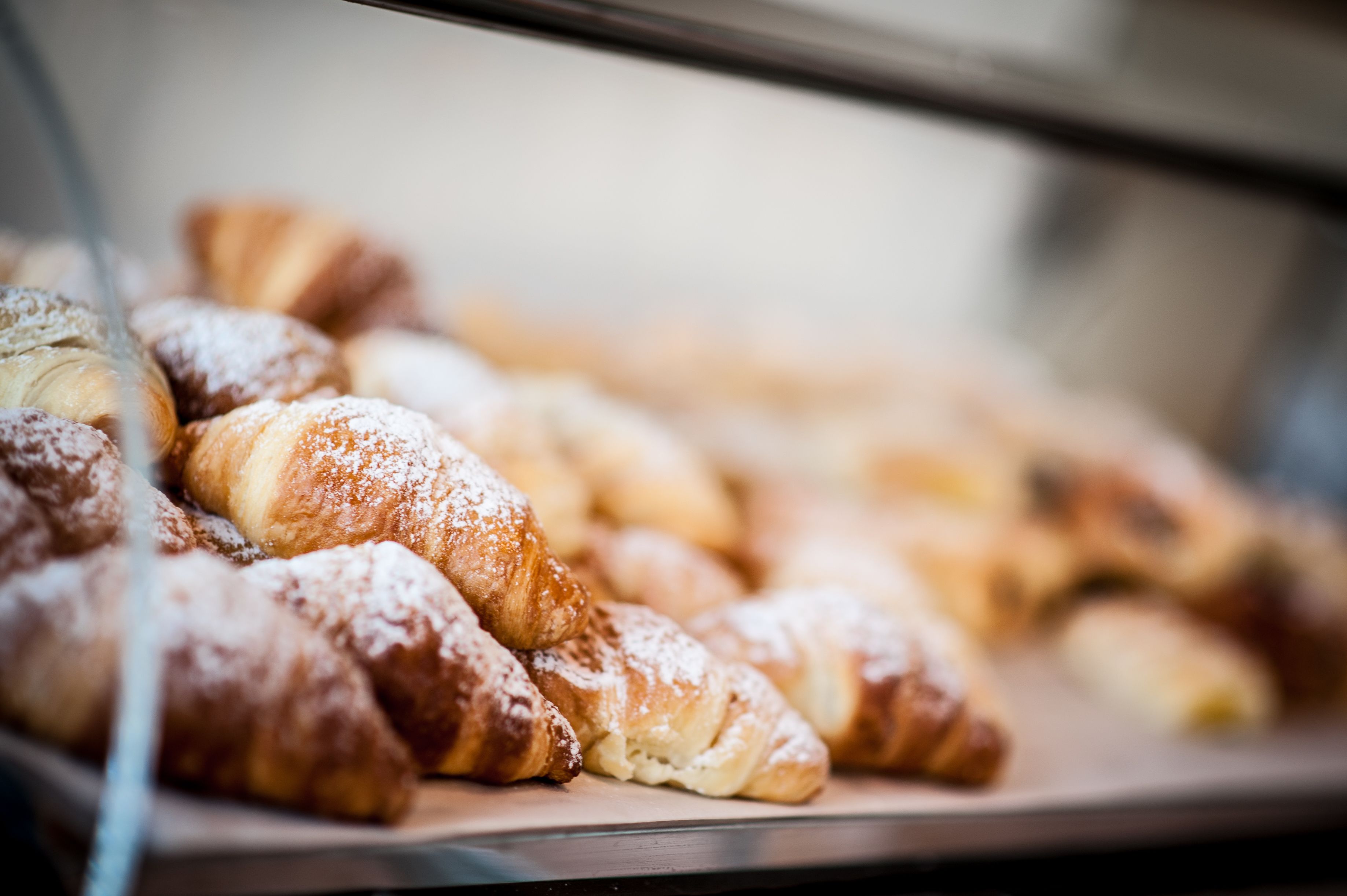 Una vitrina con diversos pasteles, incluyendo croissants y otras delicias horneadas.
