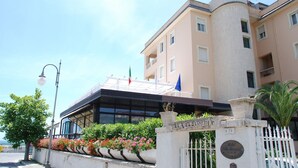 A hotel entrance with a gated driveway, a flag, and a sign indicating the name 'Villa Eleonora'. - Hotel Villa Eleonora (Minturno)