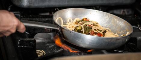 A wok on a stove with noodles and vegetables being cooked.