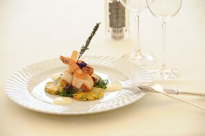 Une assiette de nourriture, une fourchette et deux verres à vin sont posés sur une table.
