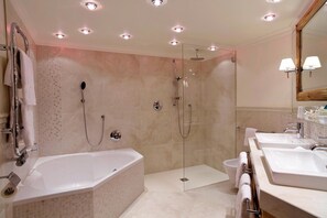 Une salle de bain moderne dotée d’une grande baignoire, d’une douche à l’italienne et de deux lavabos.